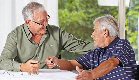Foto de dos ancianos hablando de papeleo y sonriendo.